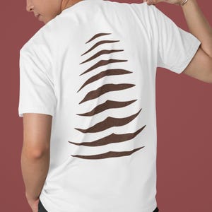 May include: White t-shirt with a brown claw mark design on the back. The claw marks are arranged vertically, creating a unique and eye-catching graphic. The shirt is made of a soft material.