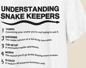 May include: White t-shirt with black text that reads "Understanding Snake Keepers" and a numbered list of snake keeper terms. The list includes: 1. Taming, 2. Shedding, 3. Tub Setup, 4. Morph, 5. Cloaca.