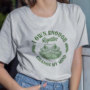 May include: A white t-shirt with a green graphic that says "I own enough reptiles to change my mind". The graphic features a bearded dragon.