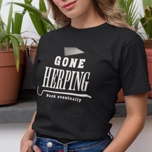 May include: Black t-shirt with the white text "GONE HERPING" above "Back eventually". The shirt has a crew neck and short sleeves. The text is in a bold, sans-serif font.