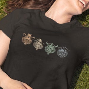 Może przedstawiać: Czarny T-shirt z grafiką czterech brodatych smoków w różnych kapeluszach: kowbojskim, czarodzieja, wikinga i pirata.