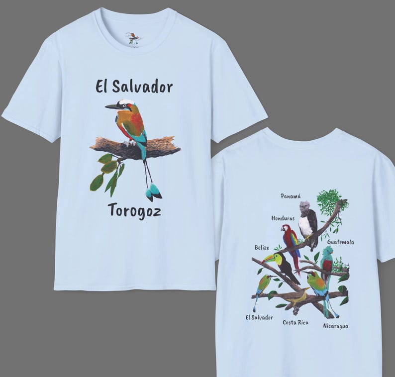 May include: Light blue t-shirt with a colorful bird illustration and the text "El Salvador Torogoz". The back of the shirt features a branch with colorful birds and the names of Central American countries.
