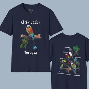 May include: Two navy blue t-shirts with a central image of a bird. The front shirt features a colorful bird with the text "El Salvador Torohoz". The back shirt features a variety of birds with the text "Panama, Honduras, Belize, Guatemala, El Salvador, Costa Rica, Nicaragua".