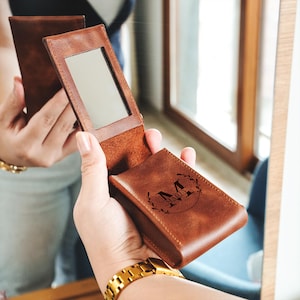 a person holding a wallet and a mirror