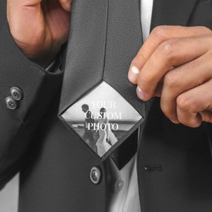 Puede incluir: Una corbata negra con un inserto blanco en forma de diamante que presenta una foto en blanco y negro de una pareja. El texto "YOUR CUSTOM PHOTO" está impreso en el inserto.
