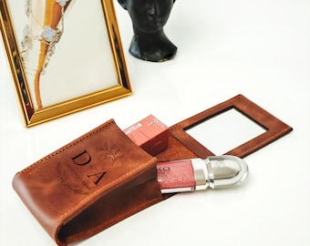 May include: A brown leatherette makeup bag with a mirror and a personalized inscription that reads "DA David And Anna". The bag is open and a clear lip gloss tube is visible inside.