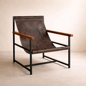 May include: A lounge chair featuring a dark brown leather sling seat suspended within a black metal frame. The chair includes two horizontal wooden armrests attached to the top of the black metal side supports, creating a structured open design.