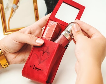 May include: Red leather makeup bag with a mirror, a lipstick, and a lip gloss. The bag has a floral design and the name "Anna" is engraved on the front.