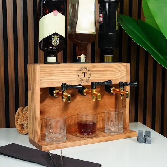 A wall-mounted engraved wood liquor dispenser with glasses — functionally unusual and visually striking compared to every other decanter in this set.