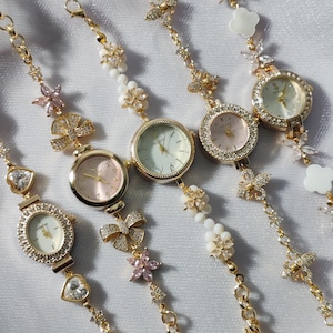 May include: Five gold-tone wristwatches with jeweled bezels and delicate floral and bow-shaped charms on the bands.