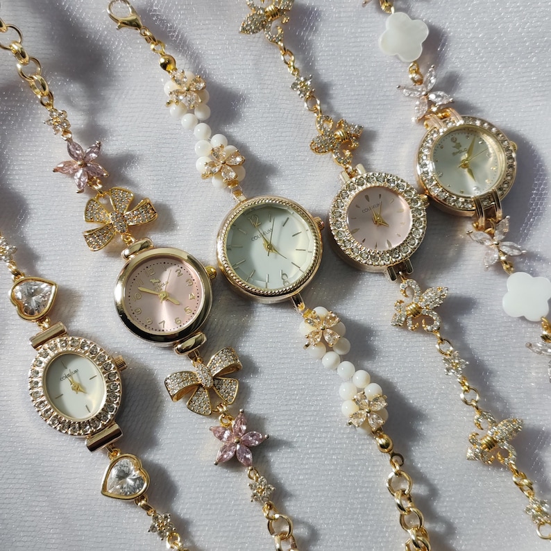 May include: Five gold-tone wristwatches with jeweled bezels and delicate floral and bow-shaped charms on the bands.