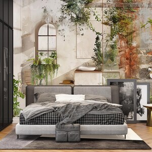 May include: A modern bedroom with a gray upholstered bed featuring a black and white patterned bedspread. A gray briefcase sits at the foot of the bed. The room has a neutral color palette with a distressed wall mural and a gold side table.