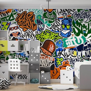 May include: A colorful graffiti-style wall mural with various cartoon characters and text. The room features white furniture, including a desk, chair, and storage units. A bed and decorative rug complete the room's design.