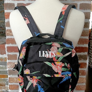 May include: A white ceramic mug with a black handle and the text "But First, Coffee" in a black, handwritten-style font. The mug is on a white surface.