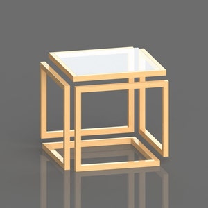 May include: A gold-toned metal side table with a square top and a geometric design. The table has a glass top and is made of multiple layers of metal.