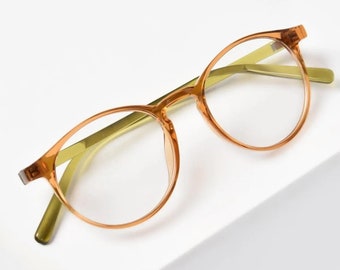 May include: Orange-tinted round eyeglasses with a gold metal frame.