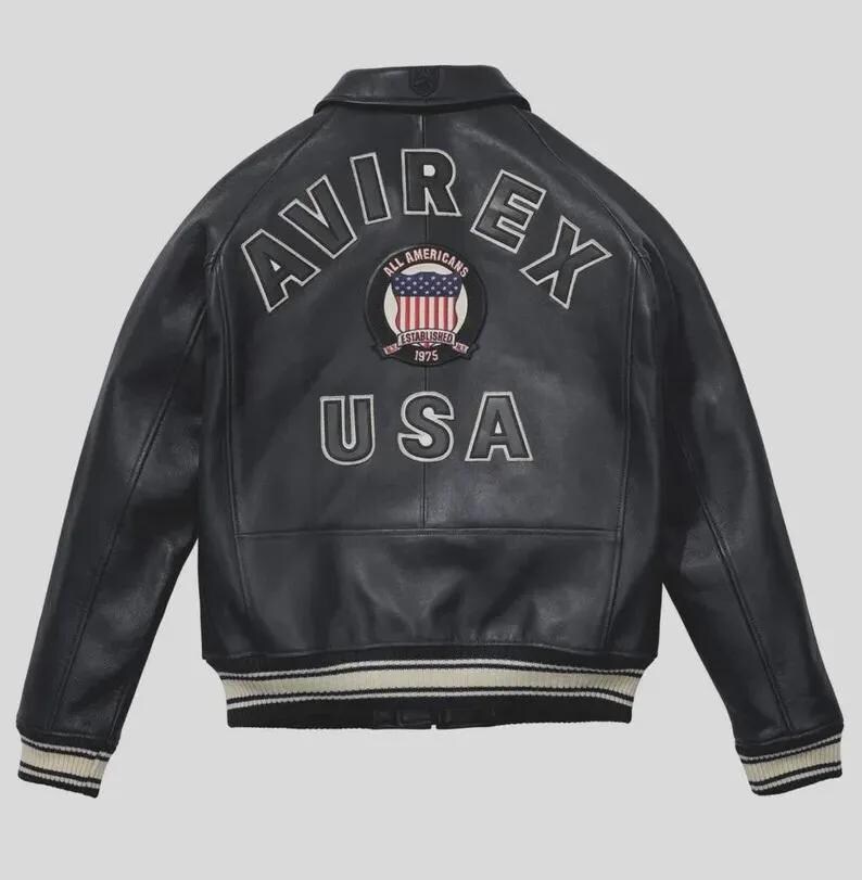 Men's black lamb leather Avirex bomber jacket with embroidered USA patches, varsity striped ribbed cuffs, and classic American flight jacket styling.