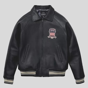 Men's black lamb leather Avirex bomber jacket with embroidered USA patches, varsity striped ribbed cuffs, and classic American flight jacket styling.