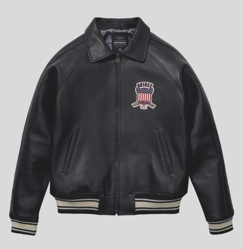 Men's black lamb leather Avirex bomber jacket with embroidered USA patches, varsity striped ribbed cuffs, and classic American flight jacket styling.