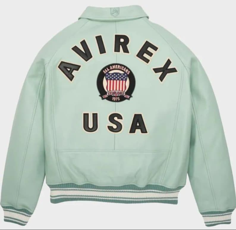 May include: A light green leather jacket with the word "AVIREX" arched across the back in black letters. Below the word "AVIREX" is a circular patch with the words "ALL AMERICANS" and "ESTABLISHED 1975" surrounding a graphic of the American flag. The word "USA" is below the patch.