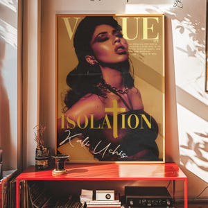 May include: A magazine cover featuring a woman with dark hair and makeup, wearing a black top. The magazine is titled "VUE" and the cover story is "ISOLATION" by Kali Uchis.