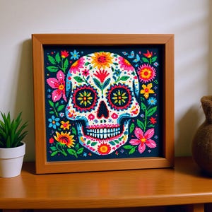 May include: A framed cross-stitch picture of a sugar skull, decorated with vibrant flowers in pink, yellow, blue, and green. The skull is set against a dark blue background and enclosed in a wooden frame.