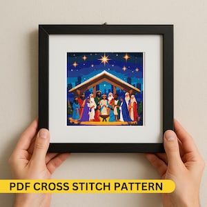 Puede incluir: Un patrón de punto de cruz enmarcado que representa una escena de la natividad con figuras con coloridas túnicas bajo un refugio de madera. El fondo presenta un cielo estrellado y el texto "PDF CROSS STITCH PATTERN" en una pancarta amarilla.