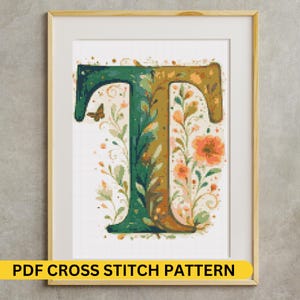 May include: A framed cross-stitch pattern featuring the letter "T" in shades of green and gold, adorned with floral and leaf motifs. A small butterfly is visible. The text "PDF CROSS STITCH PATTERN" is displayed on a yellow banner at the bottom.