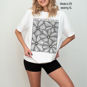 May include: White oversized t-shirt with a black and white graphic print of flowers. The graphic says "Farht Laughs in Flowers" and "Fight With Emerson".
