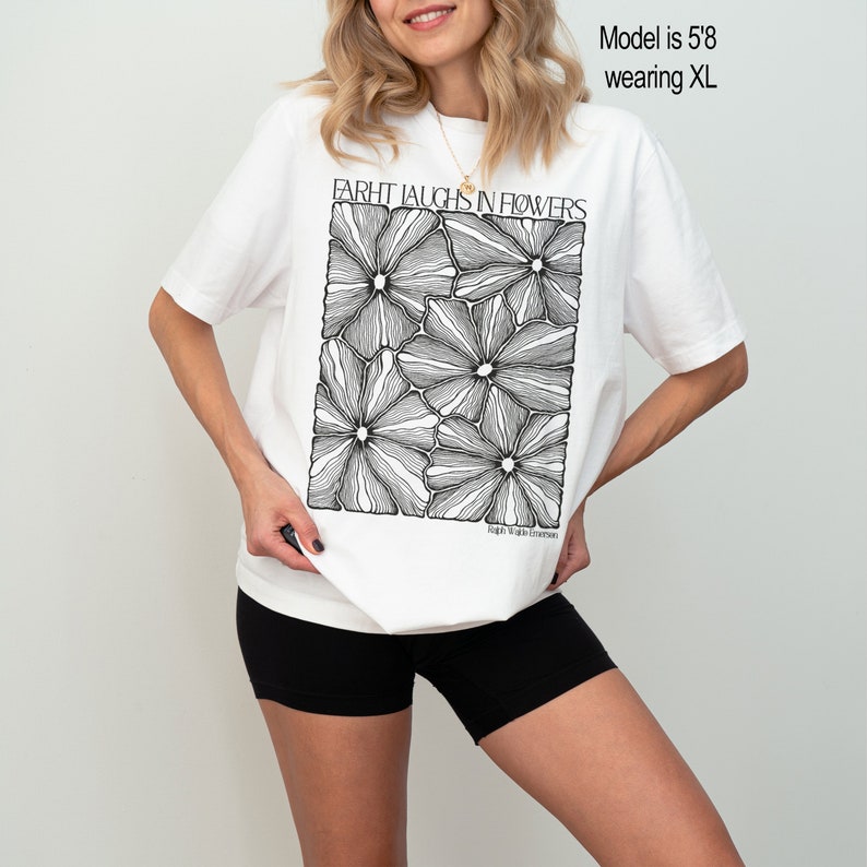 May include: White oversized t-shirt with a black and white graphic print of flowers. The graphic says "Farht Laughs in Flowers" and "Fight With Emerson".