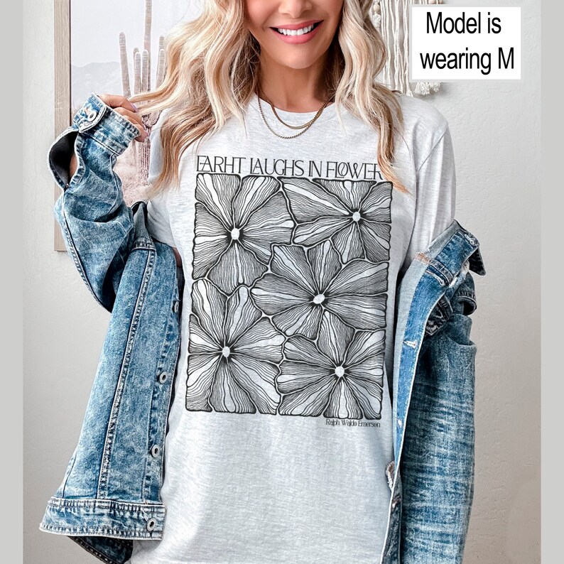 May include: A gray t-shirt with a black and white graphic of stylized flowers. The text "FARHT LAUGHS IN FLOWER" is printed on the shirt. The text "High Wilde Emerson" is printed below the graphic.