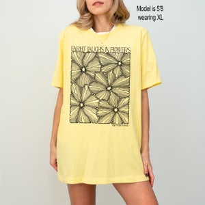 May include: A yellow t-shirt with a black graphic of flowers and the text "EARTH LAUGHS IN FLOWERS" and "People. Plants. Emerson."