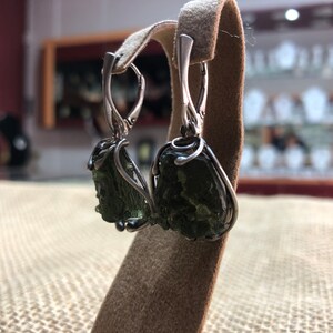 May include: Silver earrings with green aventurine stones wrapped in wire. The stones are rough and natural.
