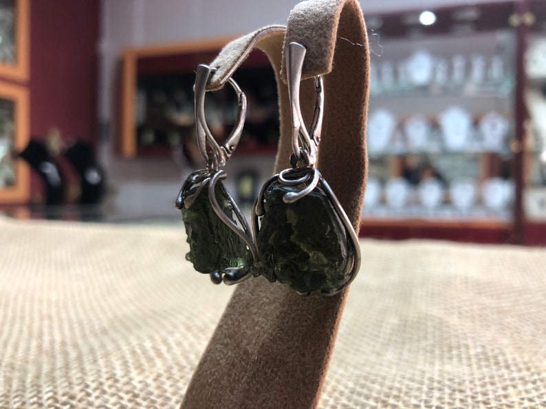 May include: Silver earrings with green aventurine stones wrapped in wire. The stones are rough and natural.