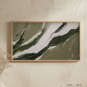 May include: Abstract painting in shades of green and white with a textured, marbled effect. The painting is framed in a light wood frame and is hanging on a beige wall.