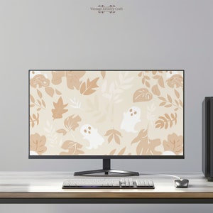 May include: A computer monitor displaying a digital desktop background with a pattern of white ghosts and brown leaves on a beige background. The monitor is on a desk with a keyboard and a mouse.