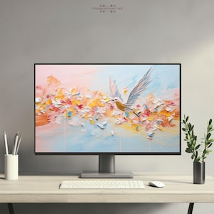 May include: A computer monitor displaying a digital painting of a white bird flying through a field of pink, yellow, and blue flowers. The monitor is on a wooden desk with a white keyboard and a white mouse.