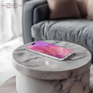 May include: A white smartphone with a pink and purple abstract design on the screen. The phone is lying on a white marble surface.