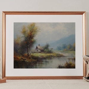 May include: A framed oil painting depicting a rural landscape with a small house by a river. The scene is painted in muted tones of blue, green, and brown, with a hazy atmosphere. The house is a simple structure with a wooden roof and a small window. The river is calm and reflective, with trees lining its banks.