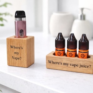 May include: Wooden vape holders with engraved text. One holds a pink vape device, the other holds three vape juice bottles. Text on the holders reads "Where's my Vape?" and "Where's my vape juice?"