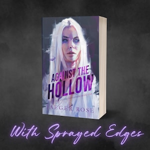 May include: A book titled "Against the Hollow" by Jaeger Rose. The cover features a portrait of a woman with white hair and blue eyes. The book has sprayed edges and is set against a dark background.
