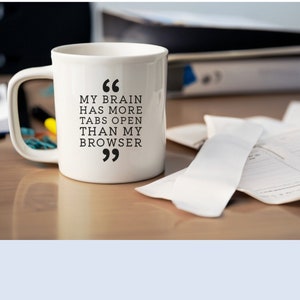 May include: White ceramic coffee mug with black text that reads "My brain has more tabs open than my browser".