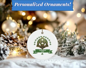 Peut inclure: Ornement de Noël en céramique blanche avec un motif de nœud celtique vert et une bannière verte avec le texte "Gallagher 2024". L'ornement est entouré d'un fond enneigé.
