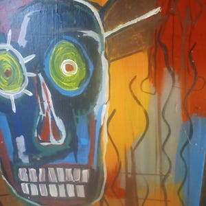 Puede incluir: Pintura abstracta de una cara azul con dientes blancos y ojos verdes sobre un fondo amarillo, naranja y marr&oacute;n.