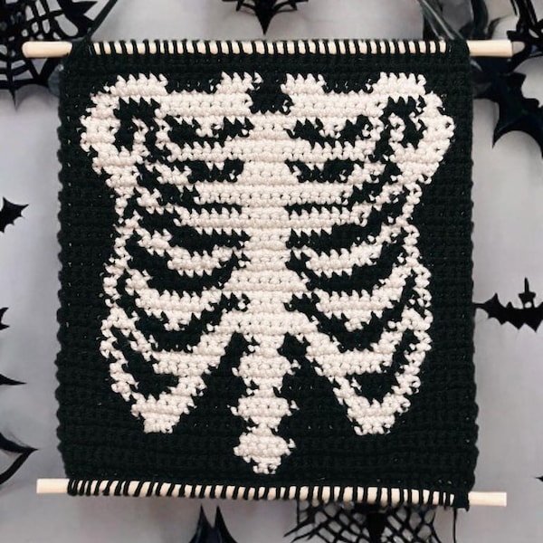 Peut inclure: Une tapisserie murale en crochet noir et blanc représentant une cage thoracique de squelette. La tapisserie est encadrée d'une baguette en bois.