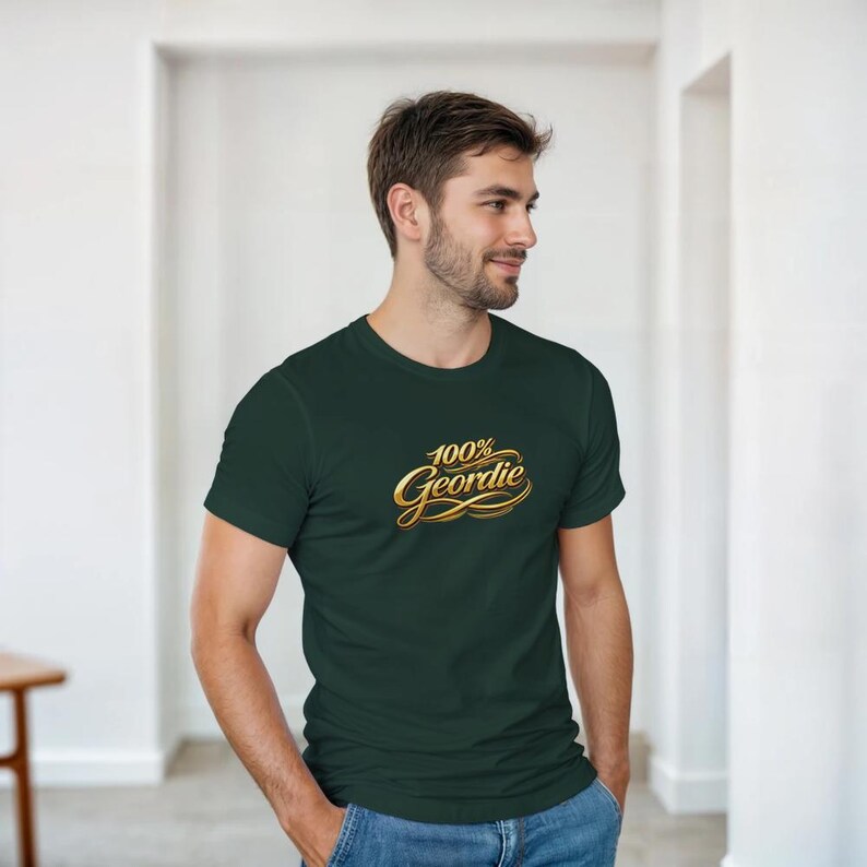 K&ouml;nnte beinhalten: Dunkelgr&uuml;nes T-Shirt mit dem goldenen Schriftzug "100% Geordie". Das T-Shirt hat kurze &Auml;rmel und einen Rundhalsausschnitt. Das Shirt ist aus weichem Material.