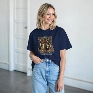 Puede incluir: Una camiseta azul marino con un dise&ntilde;o gr&aacute;fico que dice "Glasgow Style Art Nouveau Movement". El dise&ntilde;o presenta ilustraciones de personas y elementos decorativos de estilo vintage. La camiseta tiene un cuello redondo cl&aacute;sico.