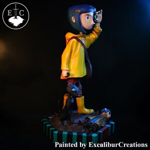 May include: A figurine of a character from the animated film, wearing a yellow raincoat and boots, looking through a small object. A black cat sits at the character's feet. The base is painted with stripes. Text: Painted by ExcaliburCreations.