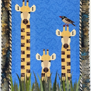 Può includere: Una colorata trapunta con tre giraffe con corpi a motivi marroni e beige e un uccellino appollaiato su una di esse. Lo sfondo è blu e la trapunta è incorniciata con un bordo a motivi.