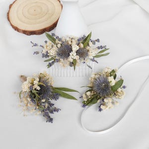 May include: Three dried flower arrangements with white and purple flowers, including a comb for hair, a boutonniere, and a wrist corsage.